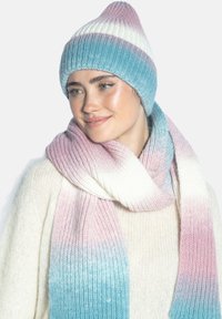 Zestaw dzianinowej czapki z daszkiem i szalika w ombre pastelowych odcieniach różu, bieli i niebieskiego, z fakturą prążkowaną i czubkiem czapki w kształcie stożka.