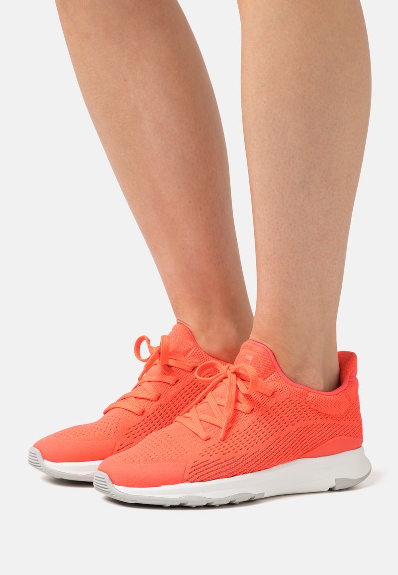 Bright coral athletic shoes with a textured mesh upper, lace-up closure, padded collar, and a white rubber sole.