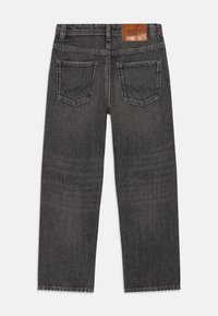 Svarte denimjeans med rett ben, med et brunt lærmerke og to baklommer. Stoffet har en subtil falming.