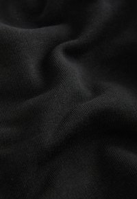 Black knit fabric with a smooth texture, showing subtle variations in weave and depth, creating a soft, draped appearance.