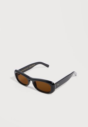 Black rectangular sunglasses with thick frames and brown tinted lenses, resting on a white surface.