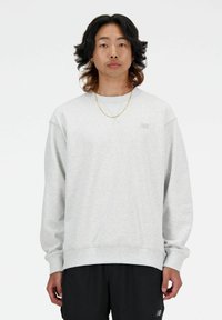 Sudadera de cuello redondo gris con puños y dobladillo acanalados. Presenta un pequeño logotipo sutil en el pecho. Fabricada con material suave y con un ajuste relajado.