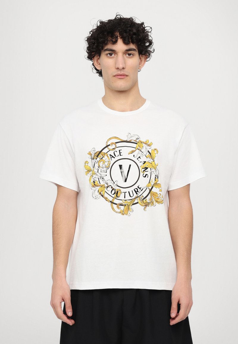Balti medvilnės marškinėliai su apvalia gėlių ornamentika, juodos ir geltonos spalvų akcentais, su užrašu "Versace Jeans Couture."