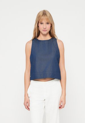 Σκούρο μπλε κοντό τοπ από τζην, με φαρδιές τιράντες, στρογγυλή λαιμόκοψη και καθαρή ραφή στο στρίφωμα. Φοριέται με λευκά λινά παντελόνια.