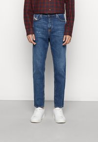 Siniset suoralahkeiset farkut, joissa viisi taskua, hieman haalistunut etuosasta ja kontrastisommiteltu. Yhdistetty valkoisiin lenkkareihin.