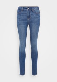Tynne jeans i middels blå denim, med høy midje, fem lommer og subtile falminger. Stoffet har en jevn tekstur og lett stretch.