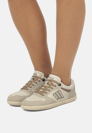 Zapatillas beige con parte superior de suave ante y cuero, con cordones marrones, suela texturizada y un detalle de logo en el lateral.