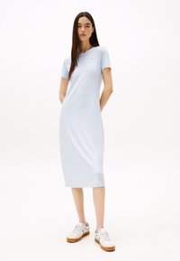 Light blue ribbed midi dress with short sleeves and crew neck; features a small logo on the chest. Worn with white sneakers.