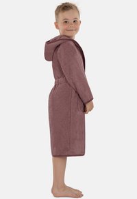 Kinder-Bademantel mit Kapuze aus weichem Frottierstoff in Mauve. Der Bademantel hat einen Gurt in der Taille, Seitentaschen und eine Länge bis zur Mitte der Wade.