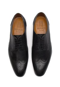 Scarpe eleganti in pelle nera con design brogue, texture liscia, punta affusolata e chiusura a lacci con perforazioni decorative.
