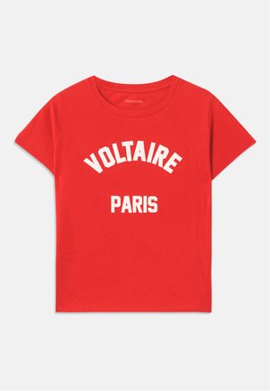 Czerwona bawełniana koszulka z krótkimi rękawami, okrągłym dekoltem i białym napisem "VOLTAIRE" oraz "PARIS" w pogrubionych, zakrzywionych literach.