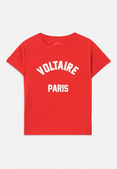 Červené bavlněné tričko s krátkými rukávy, kulatým výstřihem a bílým textem s nápisy "VOLTAIRE" a "PARIS" v tučných zakřivených písmenech.