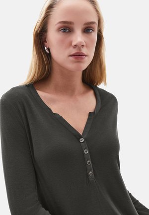 Camisa de manga larga color gris oscuro con escote en V y cinco botones metálicos en la parte delantera. Textura suave acanalada con mangas ajustadas.