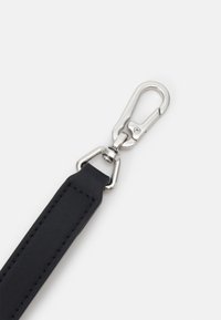 Sangle en cuir noir avec surpiqûres rectangulaires fixée à un fermoir pivotant en métal argenté et un mousqueton à ressort.