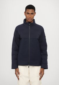 Jacheta umplută albastră cu un guler înalt și fermoar frontal. Prezintă un design minimalist și două buzunare laterale. Textură netedă, mată.