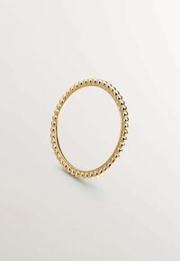 Anillo de oro con una banda circular lisa, adornado con pequeñas cuentas esféricas espaciadas uniformemente a lo largo del borde exterior, acabado pulido.