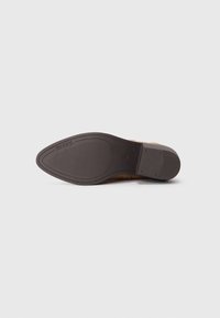Brauner Lederschuh von der Sohle betrachtet, mit dunklem Gummiprofil und spitzer Zehe.