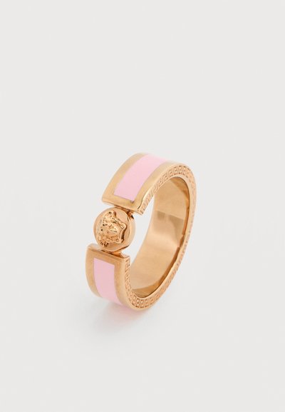 Χρυσής απόχρωσης ανοιχτό δαχτυλίδι με ροζ σμάλτο και λεπτομερή ανάγλυφη παράσταση κεφαλιού λιονταριού στο κέντρο, πάνω σε λευκό φόντο.