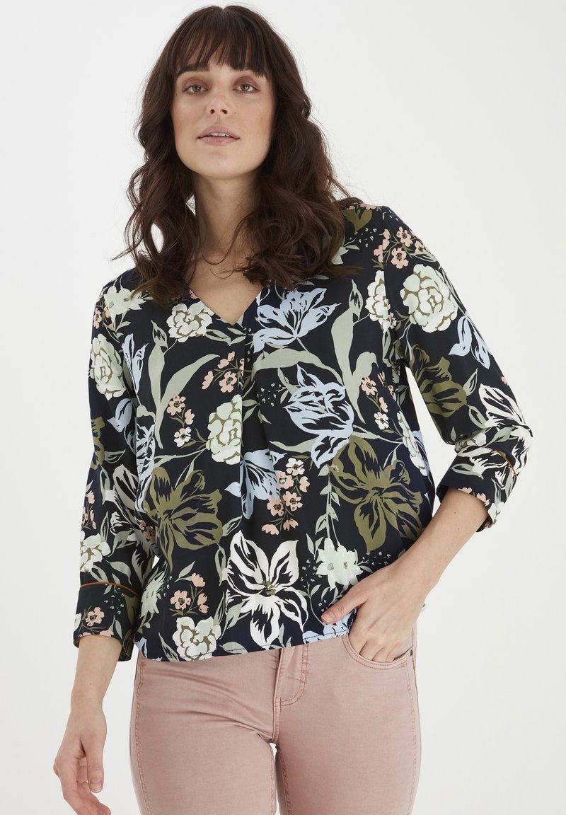 Blumenbluse mit V-Ausschnitt, dreiviertel Ärmeln, dunklem Hintergrund und mehrfarbigen Blumenmustern in verschiedenen Grüntönen, Rosa und Blau.