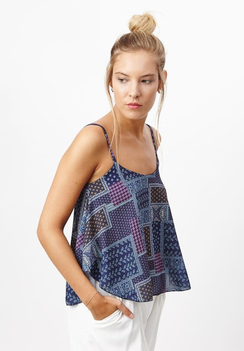 Top sin mangas de color azul marino con un diseño de patchwork que presenta patrones geométricos y florales, tejido ligero y corte suelto.