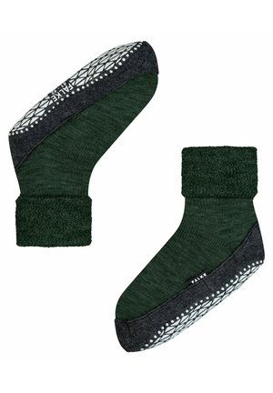 Chaussettes vertes avec une bordure épaisse et texturée, et une semelle en caoutchouc noir à motif. L'étiquette de la marque "FALKE" est visible sur le côté.