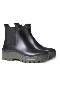 Botas de goma negras hasta el tobillo con paneles laterales elásticos. Suela verde gruesa con agarre texturizado. Superficie suave con un detalle de marca mínimo.