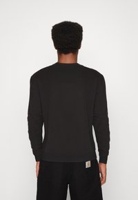Czarny sweatshirt z długimi rękawami, okrągłym dekoltem i ściągaczami na mankietach. Posiada gładką tkaninę oraz metkę z tyłu, blisko talii.