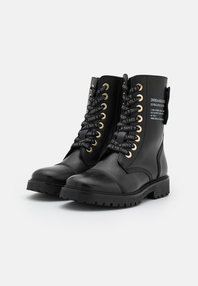 Black leather ankle boots with a round toe, gold hardware, and patterned black laces. Features a side zip and textured rubber sole.