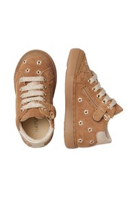 Zapatillas de ante marrón con diseño de cordones y cremallera lateral, detalles en dorado y tachuelas metálicas decorativas con forma de flor en la parte superior.