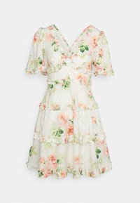 Robe courte blanche à motif floral rose et vert, manches courtes ballons, col en V et bordure volantée sur les étages.