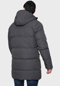 Grauer Steppmantel mit Kapuze, langen Ärmeln und einer Reißverschlusstasche am linken Arm. Das Material ist glatt und hat ein gepolstertes, gesteppte Design.