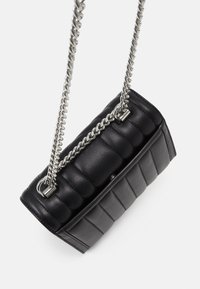 Musta nahkainen käsilaukku, jossa on tikattu pinta, varustettuna hopeisella ketjuhihnalla ja suorakulmaisella muotoilulla, korostaen tyylikkäitä suunnittelutietoja.