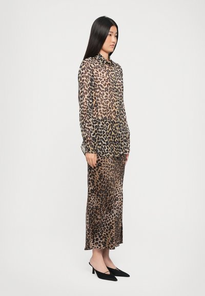 Leopard print sheer blouse and matching midi skirt, both in beige and brown tones, paired with black heeled mules.