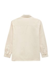 Lys beige, langærmet skjorte med krave. Har knaplukning ved ærmerne og en lige kant. Glat tekstur med syede detaljer.