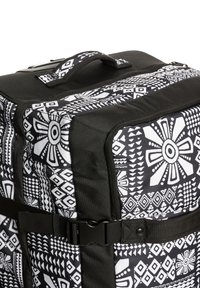 Czarny i biały plecak w geometryczne wzory, z mocną rączką i klamrą zapewniającą bezpieczne zamknięcie. Teksturowany materiał.