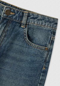 Jeans dżinsowe w ciemnoniebieskim kolorze, z klasycznym pięciokomorowym wzorem, posiadające widoczne szwy i metalowy guzik w talii.