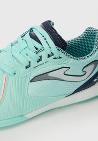 Scarpa da ginnastica in un azzurro chiaro, con tomaia in mesh, sovrapposizioni testurizzate, dettagli in blu scuro e un marchio evidente. Include lacci e collare imbottito.