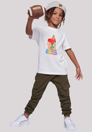 White t-shirt featuring a colorful bear graphic design, paired with olive cargo pants and white sneakers with textured accents.