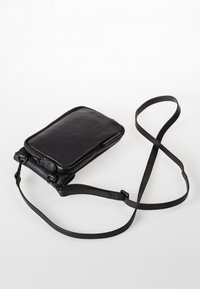 Borsa a tracolla nera in pelle con chiusura a zip, forma rettangolare, superficie liscia e tracolla regolabile. Presenta accenti hardware minimi.