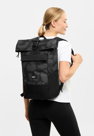 Zaino pieghevole nero realizzato in materiale resistente con un sottile motivo camouflage, spallacci regolabili e tasca frontale per l'organizzazione.