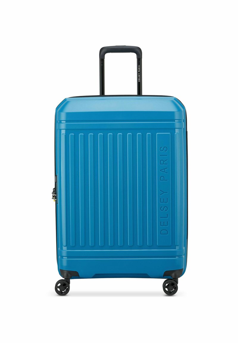 Maleta rígida de color azul brillante con textura acanalada vertical. Cuenta con un asa telescópica y cuatro ruedas negras para mayor movilidad.