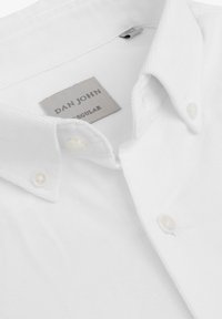 Camisa blanca de botones, hecha de algodón texturizado, con un cuello clásico, un sutil acanalado y una etiqueta gris con "DAN JOHN REGULAR."
