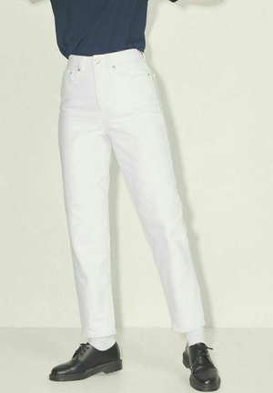 Witte denim broeken met een rechte pasvorm, voorzien van een klassieke knoopsluiting en zijzakken, gecombineerd met zwarte veterschoenen.