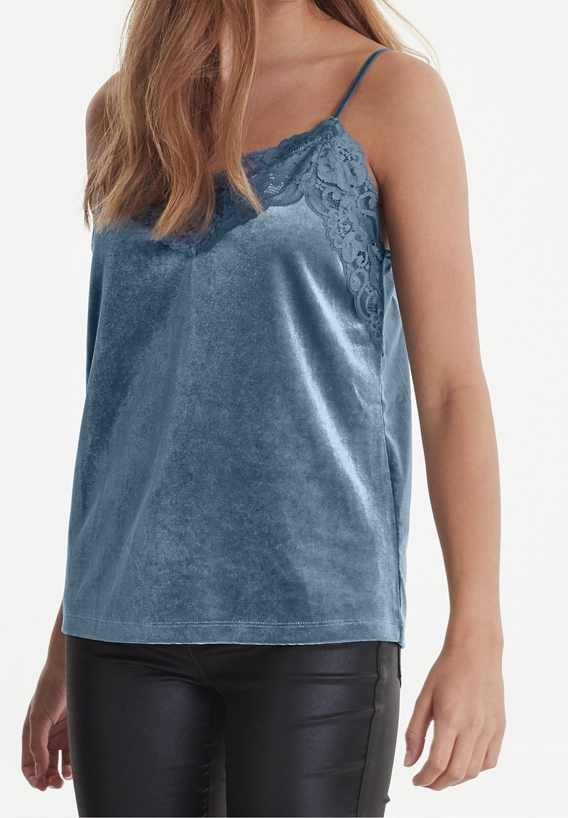 Satinblå cami med spetsdetaljer vid halsringningen, med tunna axelband och en avslappnad passform, tillverkad av ett mjukt och slätt tyg.