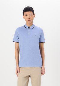 Light blue polo shirt with a black collar and cuffs, two buttons, and a small logo on the chest. Made of cotton, featuring short sleeves.