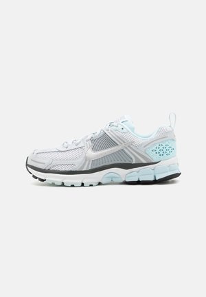Scarpa da corsa Nike bianca e azzurro chiaro con materiale in mesh, suola strutturata e logo swoosh sul lato, su sfondo semplice.
