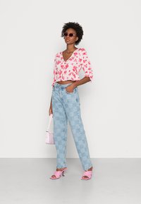 Top de flores em rosa e branco, jeans de cintura alta xadrez azul claro, sandálias de salto rosa e uma pequena bolsa rosa.