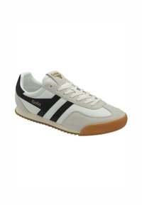 Sneaker bianca e nera realizzata in materiali scamosciati e in tela, con due righe nere, suola in gomma e logo dorato sulla linguetta.