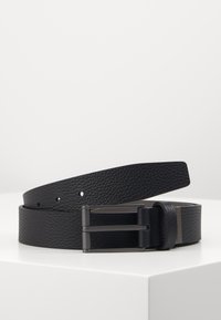 Cinturón de cuero negro con un acabado texturizado; cuenta con una hebilla de metal negro mate y múltiples agujeros de ajuste para personalizar el tamaño.