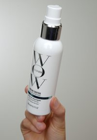 Witte cilindrische fles met een zilveren pomp. Het etiket bevat het logo "Color Wow", "Dream Cocktail" in zwarte tekst en een blauwe accentstrook. 250 ml.